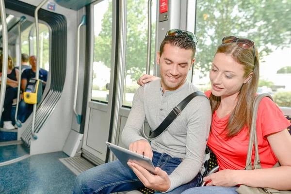 Para przy użyciu komputera typu tablet podczas podróży tramwajem — Zdjęcie stockowe