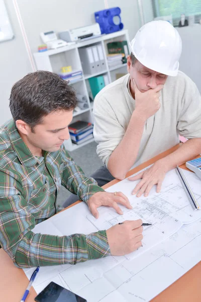 Two men in hardhats looking at blueprints — Stock Photo, Image