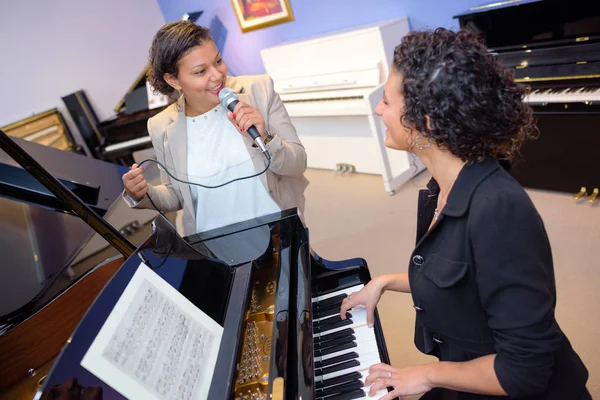 Eine Dame spielt Klavier, eine andere singt — Stockfoto