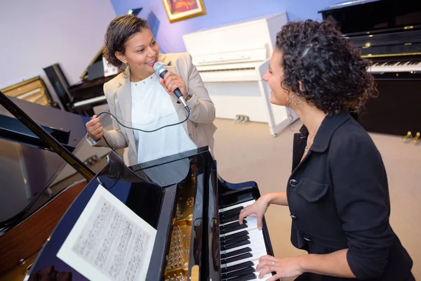 Una dama tocando el piano, otra cantando — Foto de Stock