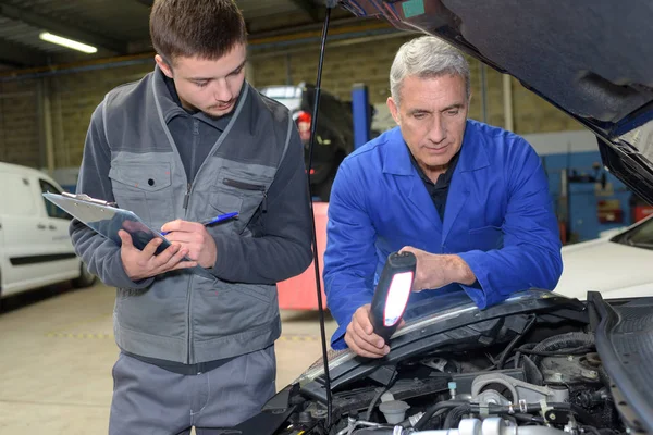 Estudante com instrutor reparar um carro durante a aprendizagem — Fotografia de Stock