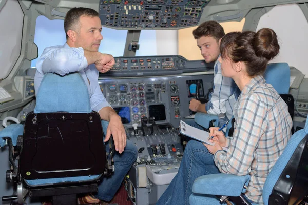 Young people questioning man in cockpit of aircraft — Stock Photo, Image