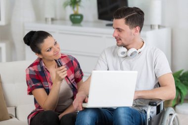 disabled man using laptop sitting next to his girlfriend clipart