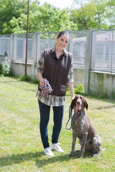 Dedicated girl training dog in kennel — Stock Photo, Image