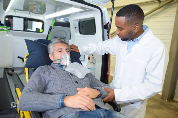 Homem usando máscara de oxigênio na maca de ambulância — Fotografia de Stock