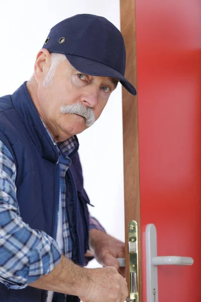 Mannelijke timmerman tot vaststelling van slot in de deur — Stockfoto