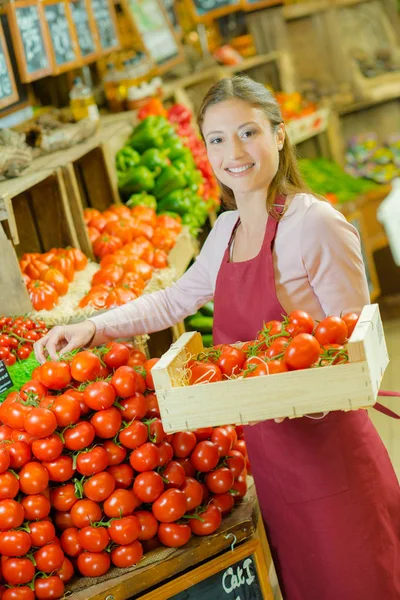 Butiksbiträde staplar upp tomater — Stockfoto