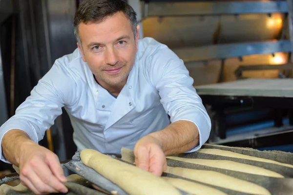 Гордый пекарь печет хлеб из багета на кухне — стоковое фото