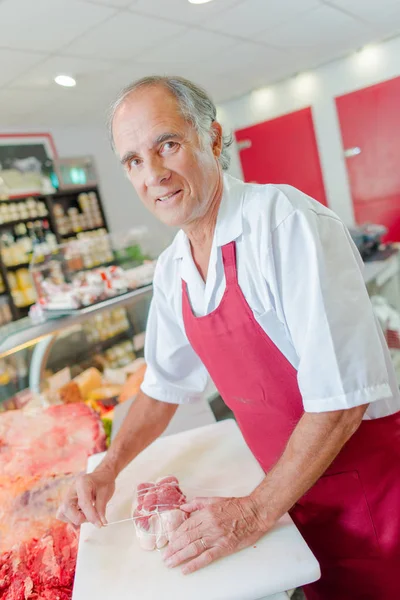 Butcher preparing a joint of beef in his shop — Stock Photo, Image