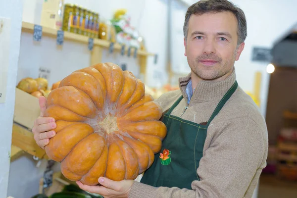 Ladenbesitzer mit großem Kürbis — Stockfoto