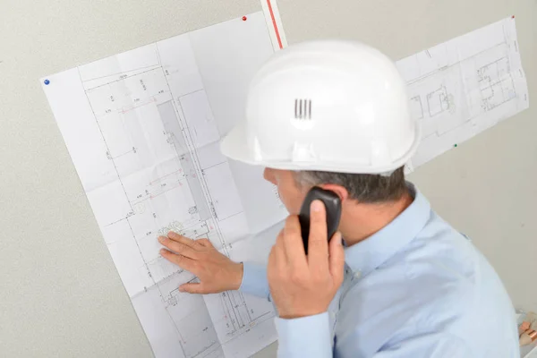 Architekt prüft Pläne mit Bauherrn am Telefon — Stockfoto