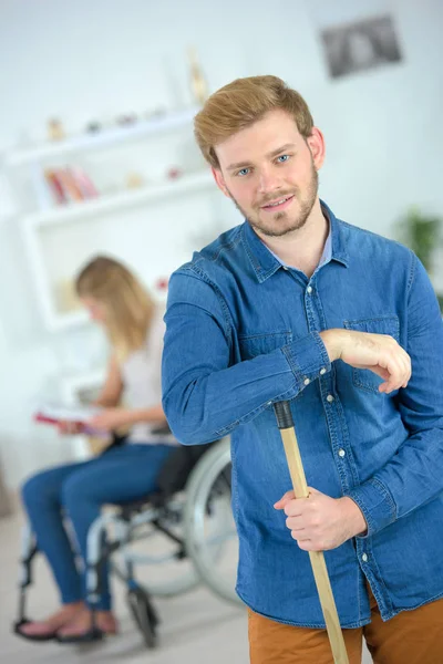Sweeping up for his disabled girlfriend — Stock Photo, Image