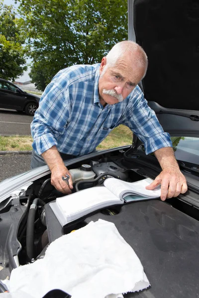 연로 한 남자는 수준을 점검하고 차를 수리 한다 — 스톡 사진