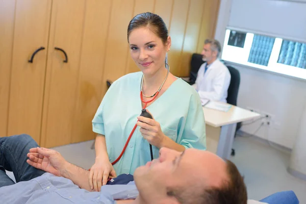 Verpleegkundige houdend van bloeddruk van de patiënt s — Stockfoto