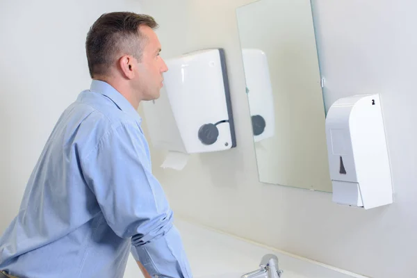 Man looking in mirror in restroom