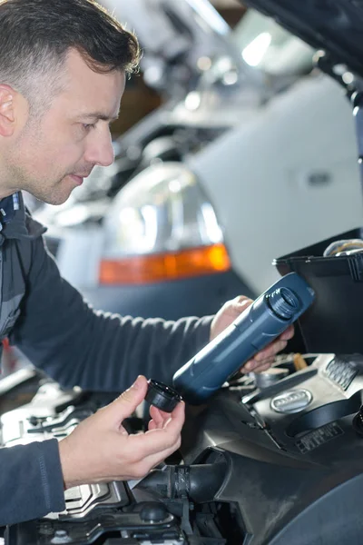 Car mechanic replacing oil on engine in garage — Stock Photo, Image