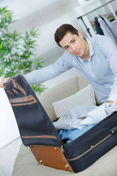 Primer plano del hombre de negocios embalaje de ropa en la bolsa de viaje — Foto de Stock