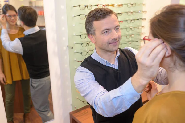 Οφθαλμίατρος και όμορφη μελαχρινή γυναίκα επιλέγοντας γυαλιά στην οπτική κατάστημα — Φωτογραφία Αρχείου