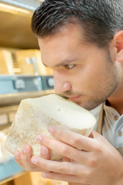 Sýr shop pracovník vonící na jeho sýrů — Stock fotografie