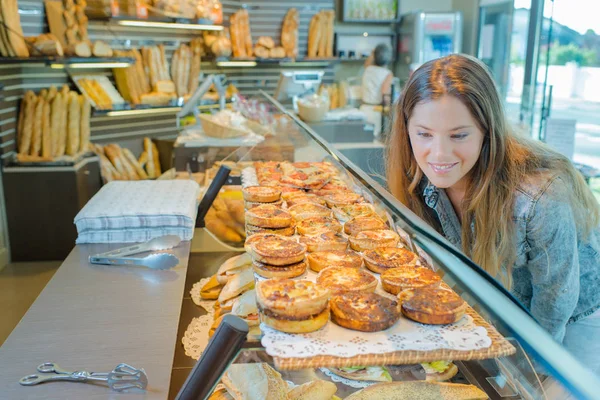 Lady in bakery looking longingly into counter — Stock Photo, Image