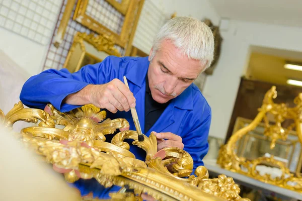 Man renovating picture frame with gold leaf — Stock Photo, Image
