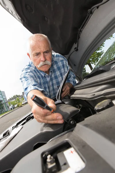 Retired man servicing his car engine — Stock Photo, Image