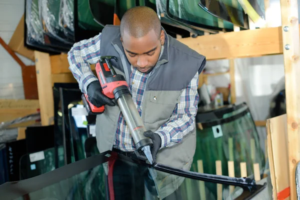 Worker putting glue on a glass — Stock Photo, Image