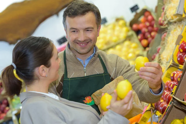 Усміхнена жінка вибирає різні фрукти на дисплеї магазину продуктів харчування ферми — стокове фото