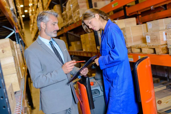 Logisitics lavoratore e il suo capo che lavorano insieme in un magazzino — Foto Stock