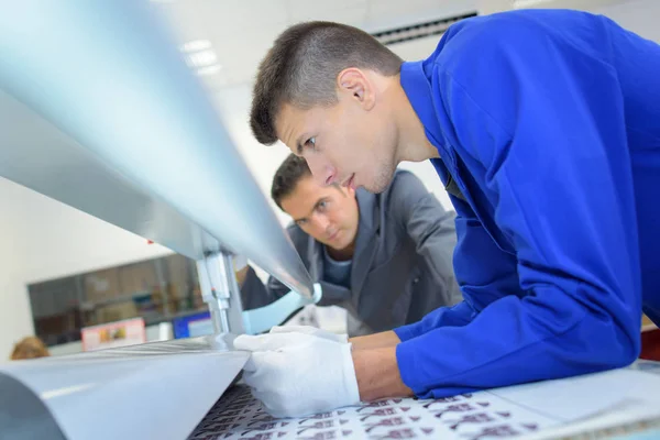 Man pulling paper through printing machine — Stock Photo, Image