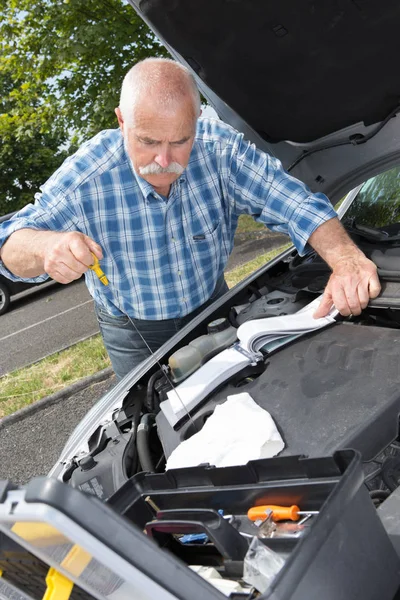 Uomo più anziano controllare i livelli e la manutenzione della sua auto — Foto Stock