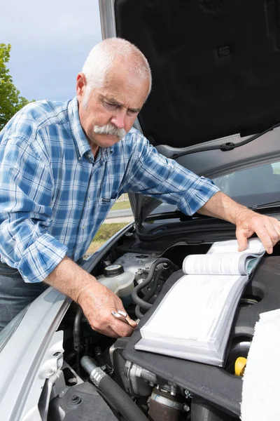 Oudere man controleren niveaus en onderhoud van zijn auto — Stockfoto