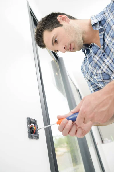 Man scewing socket aan muur — Stockfoto