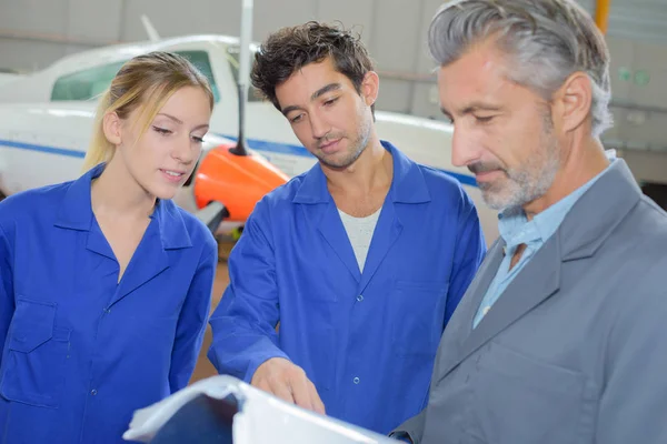 Schüler schauen sich mit Lehrer Nachschlagewerk an — Stockfoto