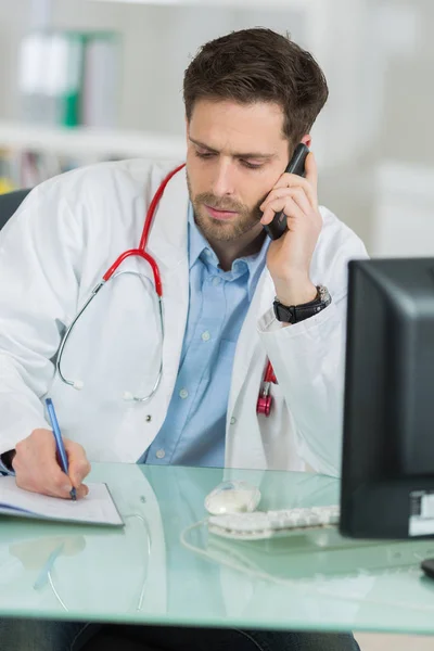 Médico masculino concentrado usando telefone no consultório médico — Fotografia de Stock