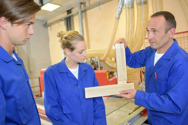 Carpenter demonstrating to two apprentices — Stock Photo, Image