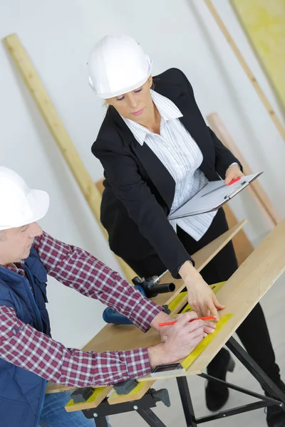 Mujer ingeniera y constructora masculina usando cascos dentro de los edificios —  Fotos de Stock