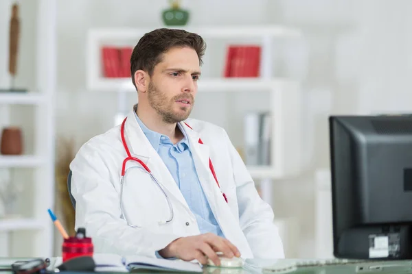 Knappe jonge dokter op het werk in zijn kantoor — Stockfoto