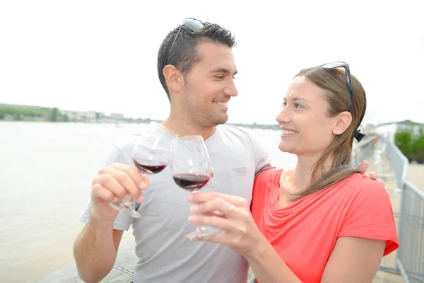 Couple au bord de la rivière, toasts au vin rouge — Photo
