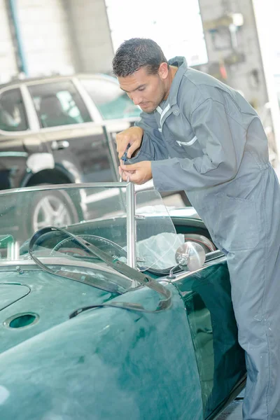 Mechanic doing up screw of windshield on classic car — Stock Photo, Image
