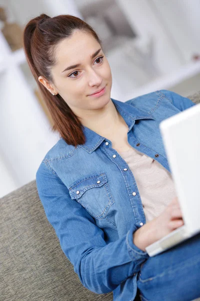 Felice ragazza seduta sul divano con computer portatile — Foto Stock