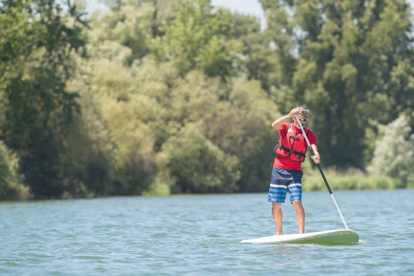 乗って paddleboard と湖を楽しむ男 — ストック写真