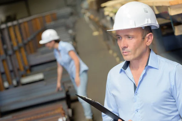 Homme dans un entrepôt industriel tenant presse-papiers — Photo