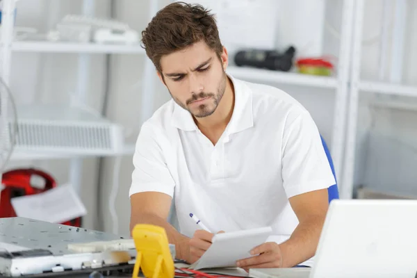 Joven ingeniero tomando notas mientras desarrolla nuevas placas de inducción — Foto de Stock