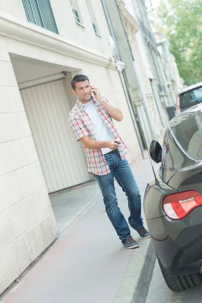 Young man phoning and unlocking his car — Stock Photo, Image