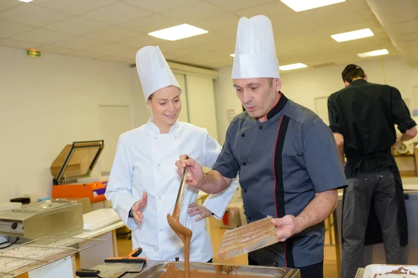 Equipo de pasteleros preparando dulces de chocolate en la cocina —  Fotos de Stock