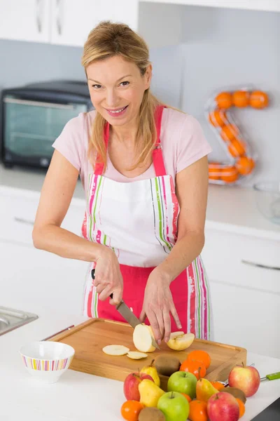 Gros plan sur des mains féminines matures tranchant des pommes sur une planche à découper — Photo