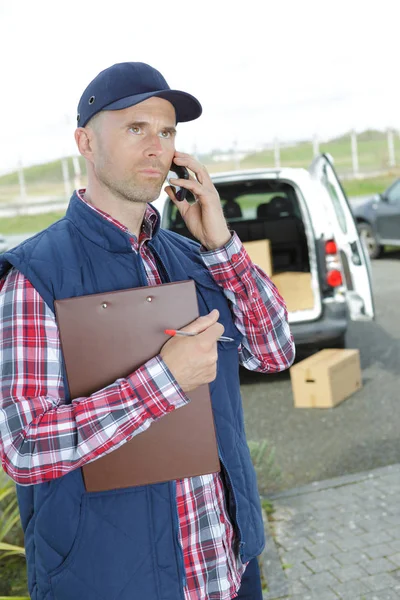 Smiling handsome delivery man making call — Stock Photo, Image