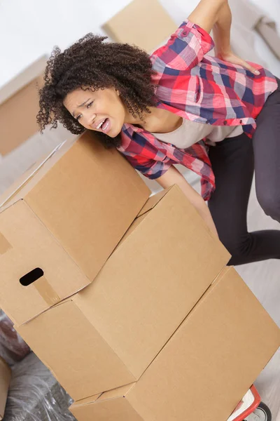 Woman with backache while lifting box — Stock Photo, Image