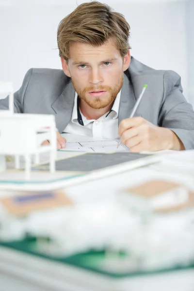 Architect making notes beside model building — Stock Photo, Image